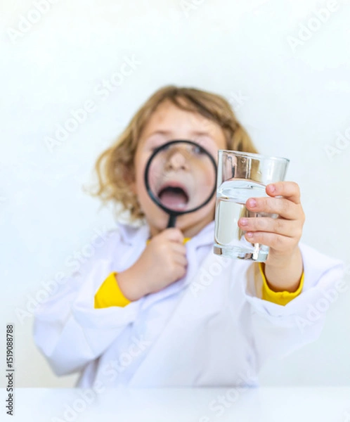 Fototapeta A child examines water with a magnifying glass. Selective focus.