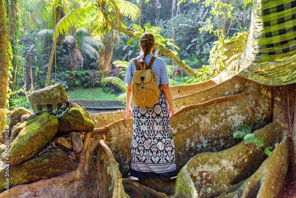 Fototapeta Female tourist with backpack enjoying view of a tropical forest
