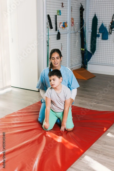 Fototapeta Physiotherapist assisting child with cerebral palsy in maintaining trunk control during quadrupedal position exercise