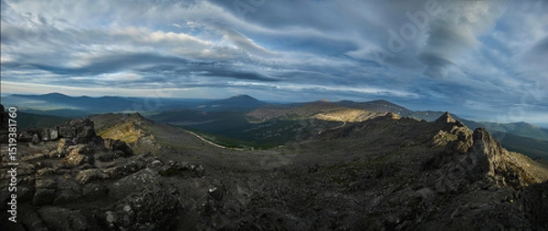 Fototapeta Breathtaking vista showcases rugged terrain interspersed with shadows and light as storm clouds drift across the sky during twilight in a mountainous area