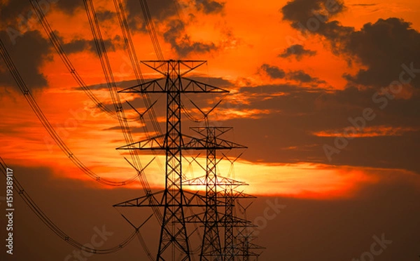 Fototapeta Silhouette of high-voltage electric pole with red-orange clouds during sunset.