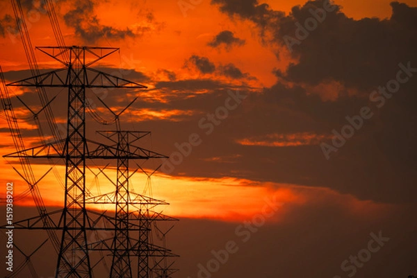 Fototapeta Silhouette of high-voltage electric pole with red-orange clouds during sunset with copy space