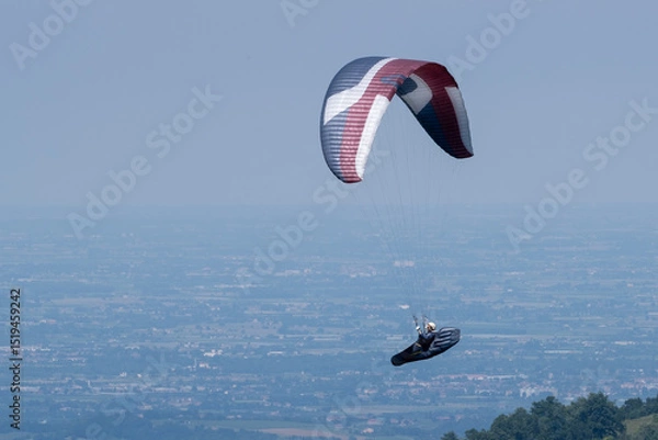 Obraz Paraglider flies in the air -Aerial view of paraglider above the mountains
