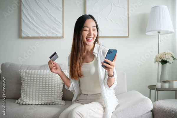 Obraz Cheerful woman managing finances, shopping online or paying bills with credit card and phone.