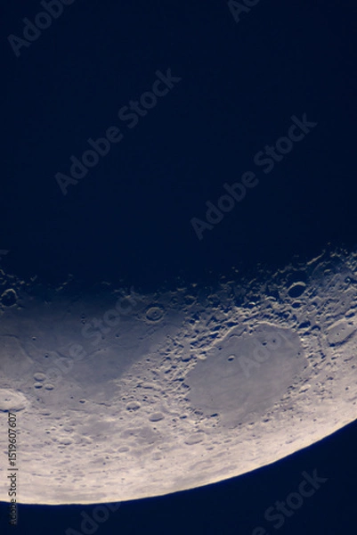 Fototapeta Crescent Moon features large crater floor and shadowed rim. Moonâ€™s terminator line, showcasing sharply defined craters, rugged mountain ranges and smooth lunar maria under low-angle sunlight