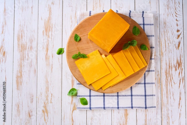 Fototapeta sliced natural cheese cheddar on on a white wooden table, top view.