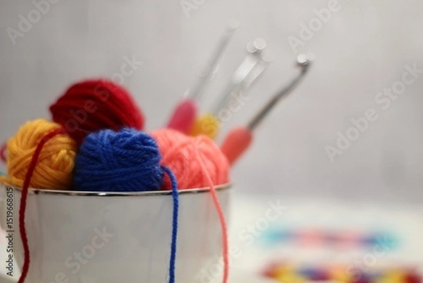 Fototapeta A cup and a saucer with clews balls of yarn wool and crocheted blanket handmade craft bright photo	