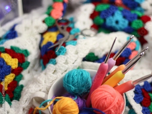 Fototapeta A cup and a saucer with clews balls of yarn wool and crocheted blanket handmade craft bright photo