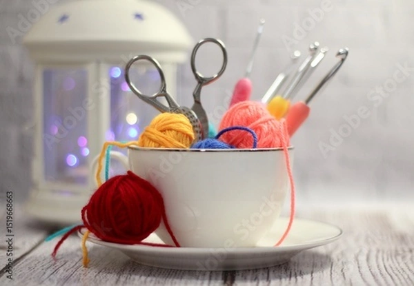 Fototapeta A cup and a saucer with clews balls of yarn wool and crocheted blanket handmade craft bright photo	