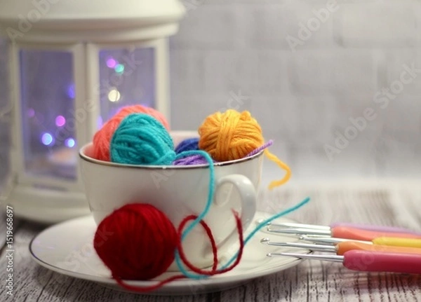 Fototapeta A cup and a saucer with clews balls of yarn wool and crocheted blanket handmade craft bright photo	