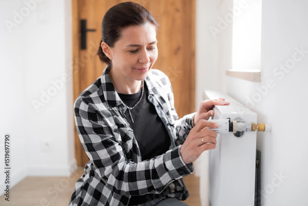 Fototapeta Girl Adjusting Heater Temperature By Rotating The Regulator