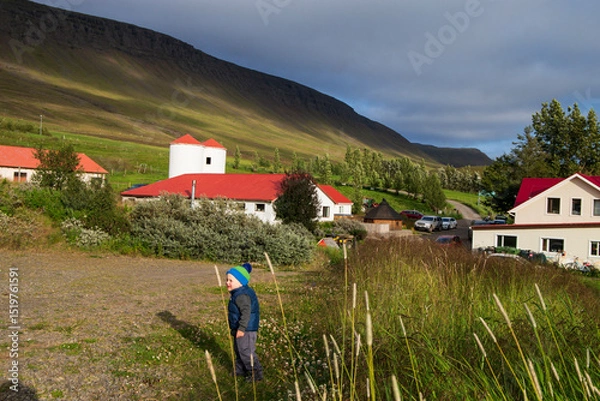 Obraz toddler boy near a traditional house surrounded by green Icelandic mountains.