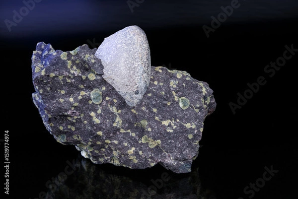 Fototapeta Natural agate gem stone in melaphyre with green amygdules on a dark shiny background. Nodule of uncut gemstone in basalt extrusive volcanic igneous rock. Mineral from northeast Czechia near Nova Paka.