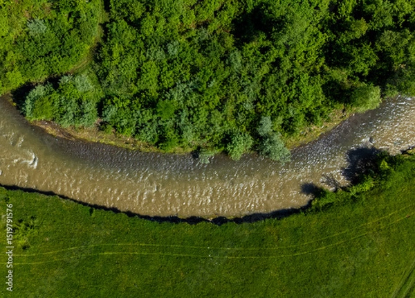 Obraz Aerial view of the Tarnava Mica river with salt-polluted water from the Praid salt mine - Romania. The place where the Corund stream flows into the Tarnava Mica river polluted with salt