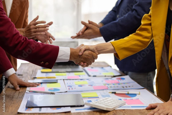 Obraz Business people shaking hands after successful meeting. Two business people shaking hands while their colleagues are clapping, after reaching an agreement during a productive meeting.