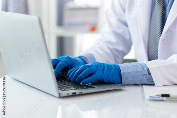 Obraz Scientist is working at a laboratory bench, typing on a laptop computer keyboard.