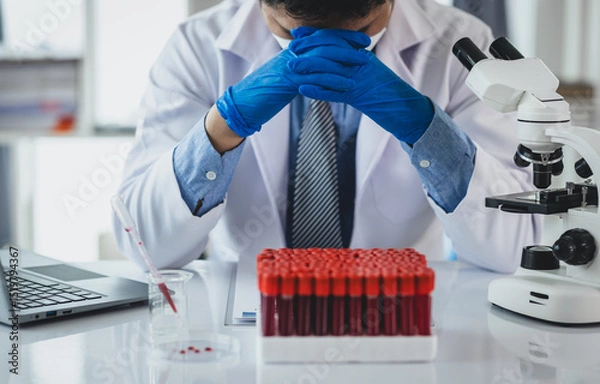 Obraz Medical scientist feeling stressed while working using microscope in laboratory, feeling stressed while doing some research, failed experiment.