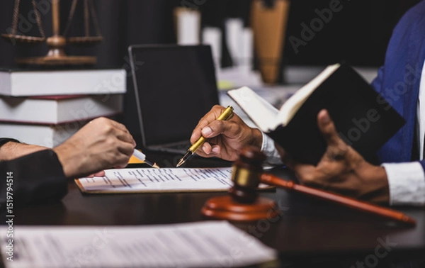 Obraz Lawyer holding law book explaining legal issues to client during a meeting. Lawyer gives legal advice to a client in an office, discussing a contract.