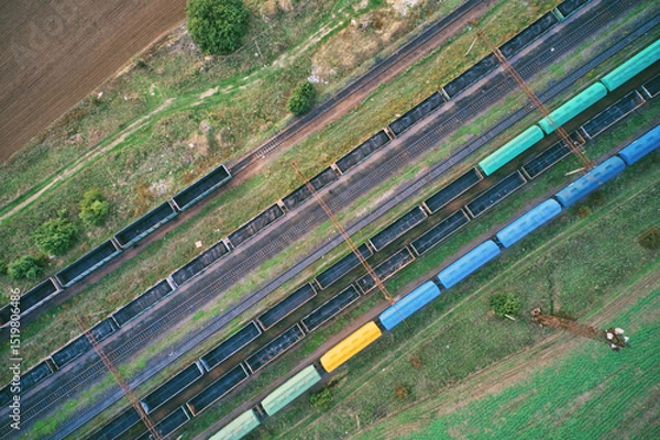 Fototapeta Aerial drone view of a freight train at a railway station, showcasing industrial transport infrastructure with steel tracks and cargo carriages. Ideal for logistics themes.
