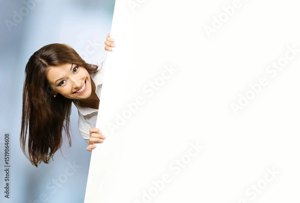 Fototapeta Image - smile brunette hair business woman businesswoman stand behind, peeping, point white blank banner mockup signboard. Success advertise concept. Free ad text space. Blurred office background