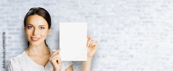 Fototapeta Smiling brunette hair business woman businesswoman wear white shirt show point blank empty banner mockup signboard. Advertise concept. Free copy space for ad text. Bricks wall background. Wide image
