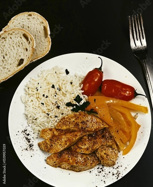 Fototapeta Roasted chicken breast dinner with rice, colorful bell pepper, and fresh tomato, served on a plate for healthy meal.