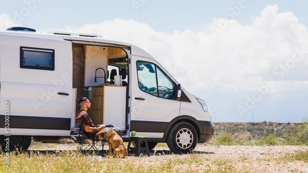 Fototapeta Man relaxing with dog in camper van at gorafe, spain