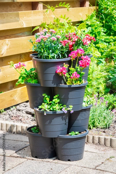Obraz Decorative sight of a tower consisting of stacked flower pots in which various brightly colored flowering plants grow