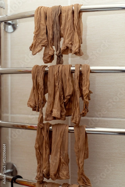 Fototapeta Yellow nylon socks drying on a heated towel rail in a bathroom, showcasing everyday laundry care at home