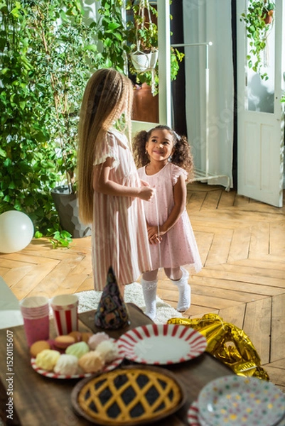 Obraz birthday party. Two little girls happily play with colorful balloons in their home