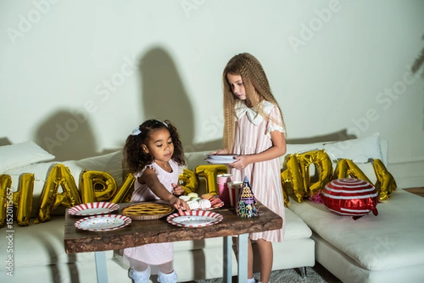 Obraz Two little girls are at a table set for a birthday party