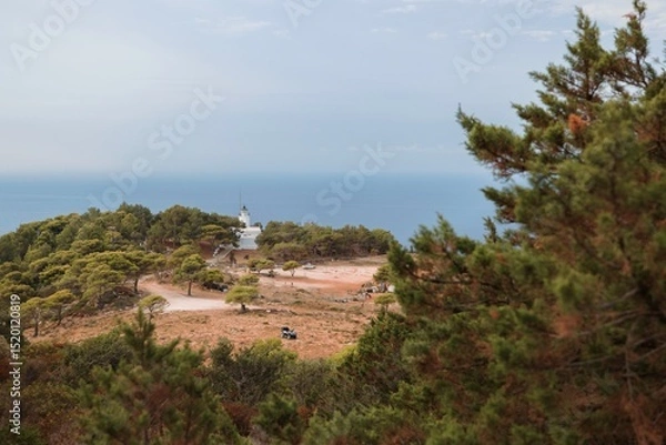 Obraz Visitors explore the breathtaking coast of Zakynthos, surrounded by lush greenery and a vibrant atmosphere. The tranquil sea meets a sky painted with soft clouds, inviting relaxation
