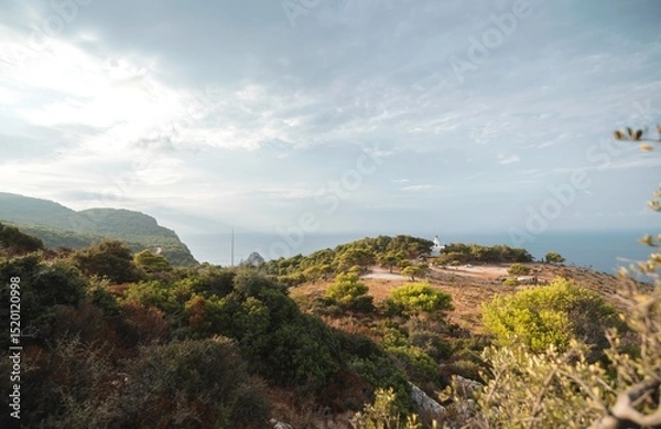 Obraz Breathtaking coastal scenery of Zakynthos captured in summer, showcasing lush greenery and dramatic cliffs meeting tranquil waters under a serene sky. Peace and adventure await