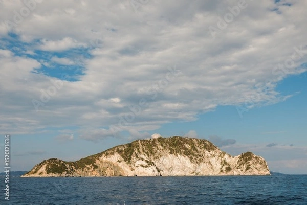 Obraz Cruising through the stunning waters of Zakynthos, visitors admire the rugged cliffs and lush greenery of the island beneath a gorgeous summer sky, creating a picturesque escape