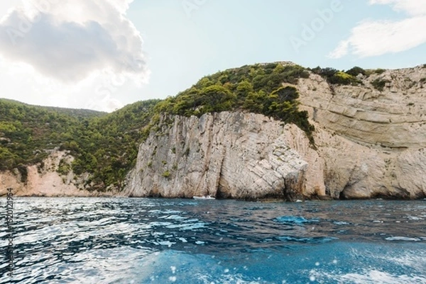 Obraz Summer adventures unfold in Zakynthos as visitors navigate the vibrant blue waters near majestic cliffs. Sunlight dances across the waves, inviting exploration and relaxation amidst nature's beauty
