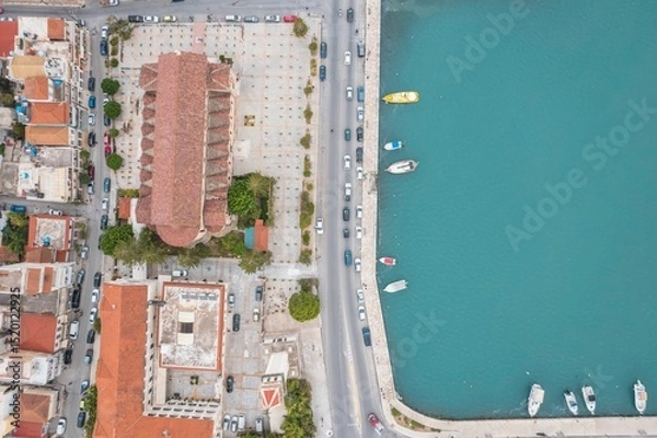 Obraz Visitors enjoy the sun-kissed streets of Zakynthos, where charming buildings and lively boats create a vibrant summer atmosphere along the beautiful coastline
