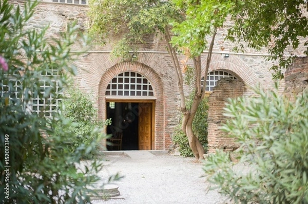Obraz Relaxation takes center stage in Zakynthos as sun-drenched courtyards invite visitors to unwind amidst lush greenery and historical architecture. A peaceful summer escape awaits