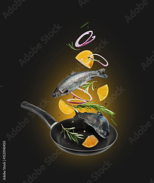 Fototapeta Sea trout with rosemary branches and lemon slices falling into frying pan on black background