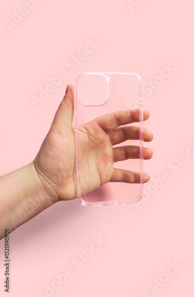 Fototapeta Clean transparent phone case displayed in hand against light pink backdrop, Modern and comfortable design