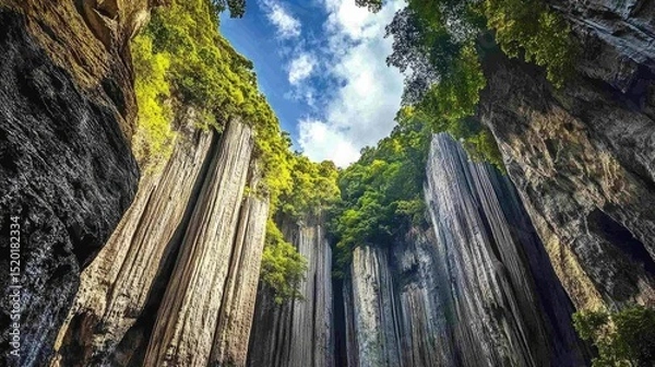 Fototapeta Massive vertical rock columns stretching toward the sky framed by dense subtropical forest