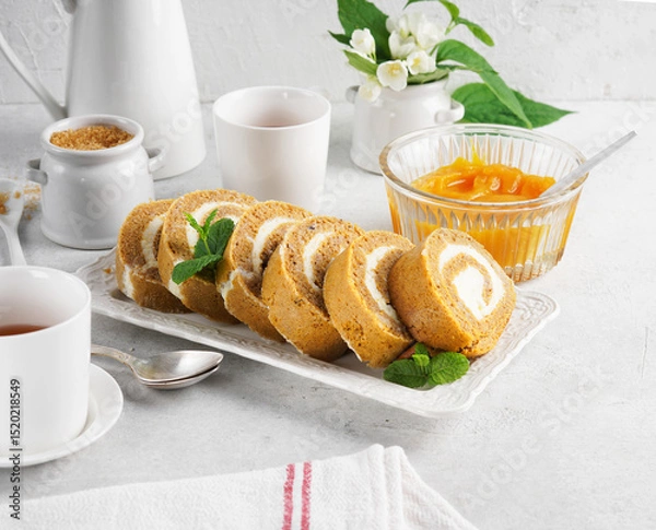 Obraz Baked pumpkin roll on a white plate with pumpkin puree of focus in the background in a breakfast kitchen scene