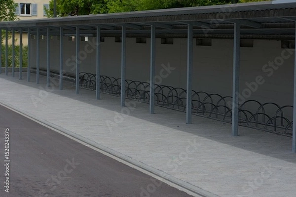 Fototapeta A row of sturdy metal bike racks under a minimalist shelter, showcasing practical urban design and organized storage solutions.