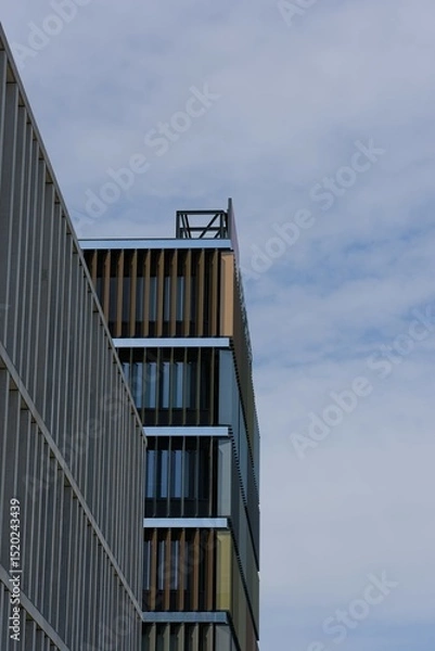 Fototapeta Modern architectural facade under a clear sky. Striking angles and clean lines dominate this urban composition.