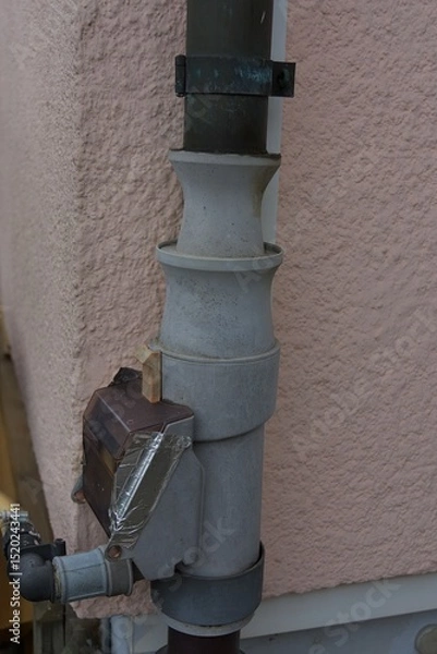 Fototapeta An intriguing outdoor pipe system with a focus on its functional details and weathered charm, set against a muted, earthy palette.