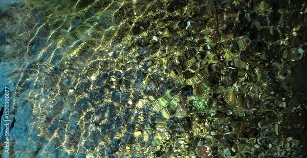 Fototapeta Colorful reflection in the moving surface of the water. Transparent water. Sandy bottom. Brilliant rays of sunlight. Spring in the wilderness. Abstract textured background