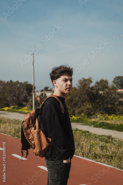 Fototapeta Man With A Backpack On The Sidewalk Waiting For The Bus To Come 