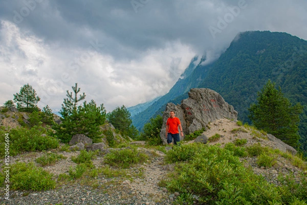 Fototapeta A man in red stands in the mountains of Georgia