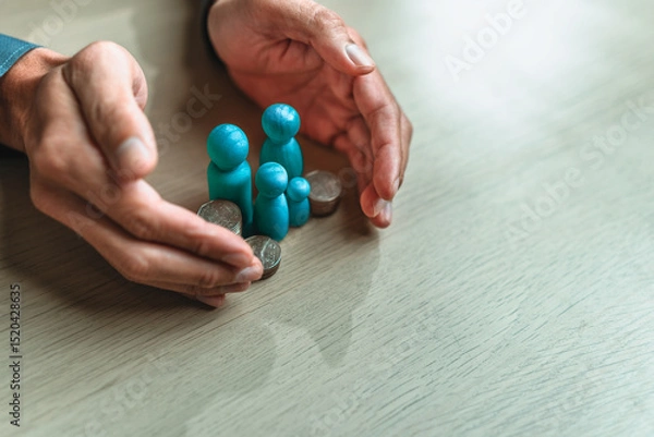 Fototapeta Businessman's hand gestures to protect money and wooden dolls represent family. Image represents the concept of asset protection, emphasizing safeguarding financial investments and property