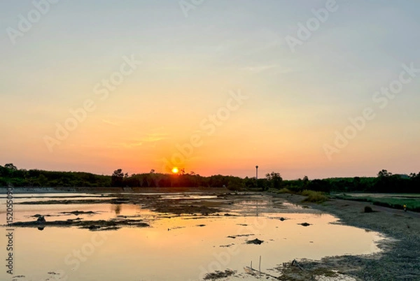 Fototapeta Sunset Over the Peaceful Waters of Talay Prong Lake in Nakhon Si Thammarat, Thailand, with Warm Light Reflecting on the Serene Landscape