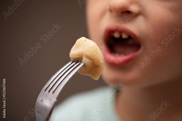 Fototapeta A closeup of a young child eating a plemeni on a fork